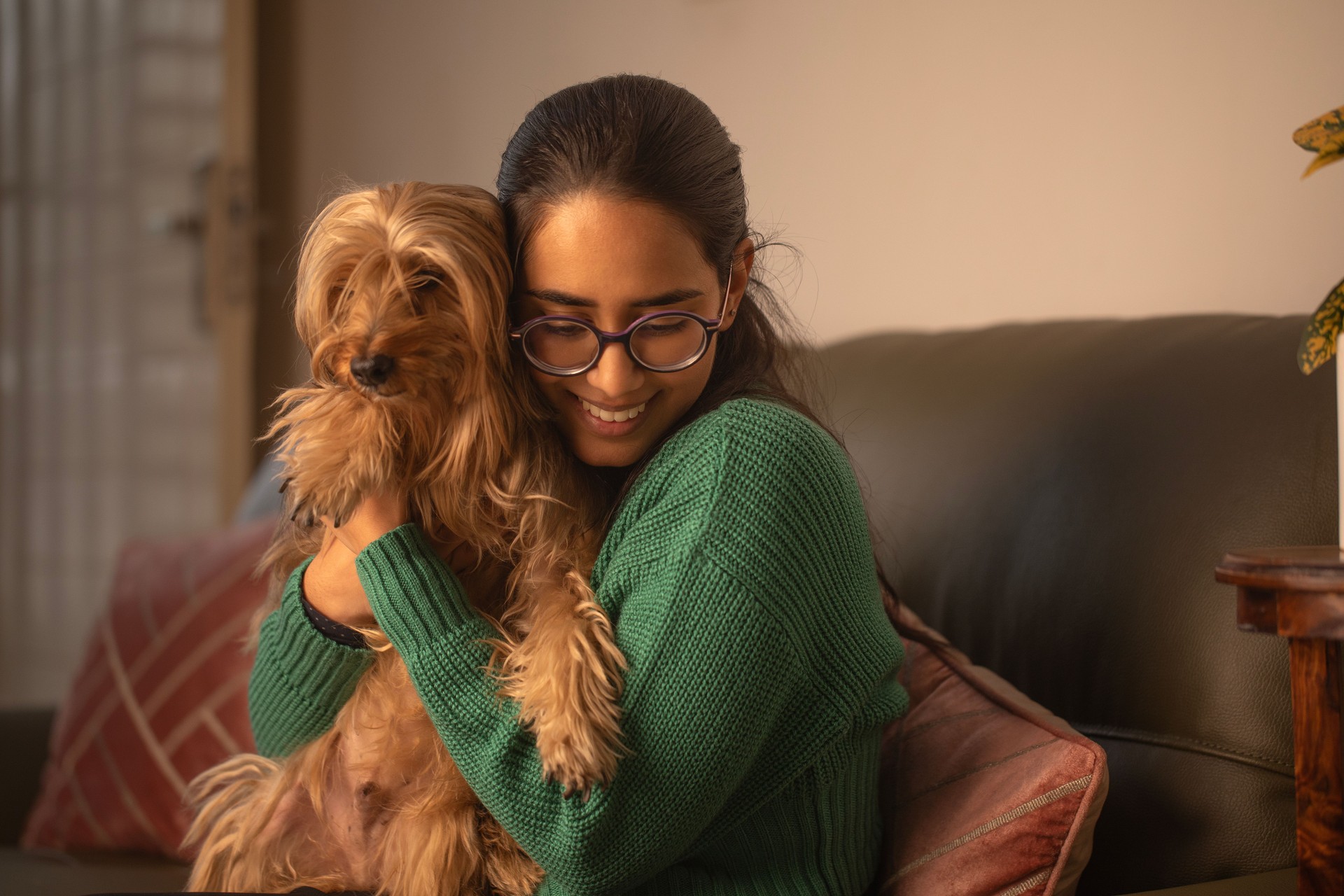 Smiling woman embracing dog on sofa